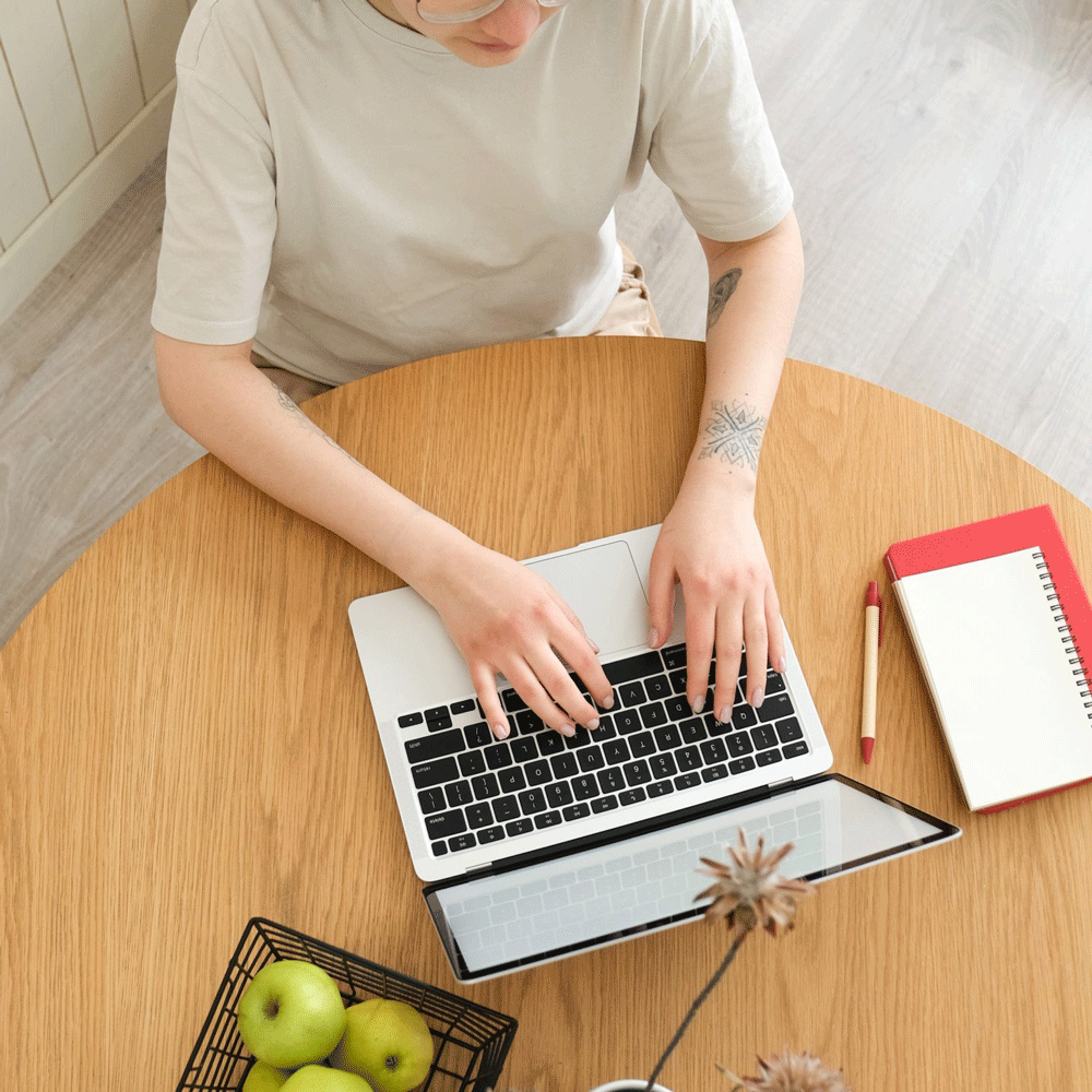 Person with tattoos typing on a laptop